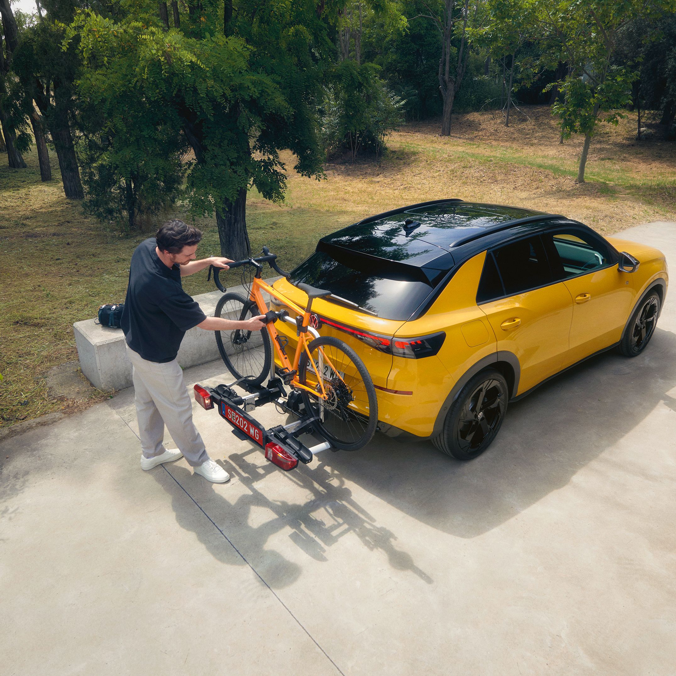 Ein Mann befestigt ein Fahrrad am Fahrradträger eines VW T-Roc R-Line.