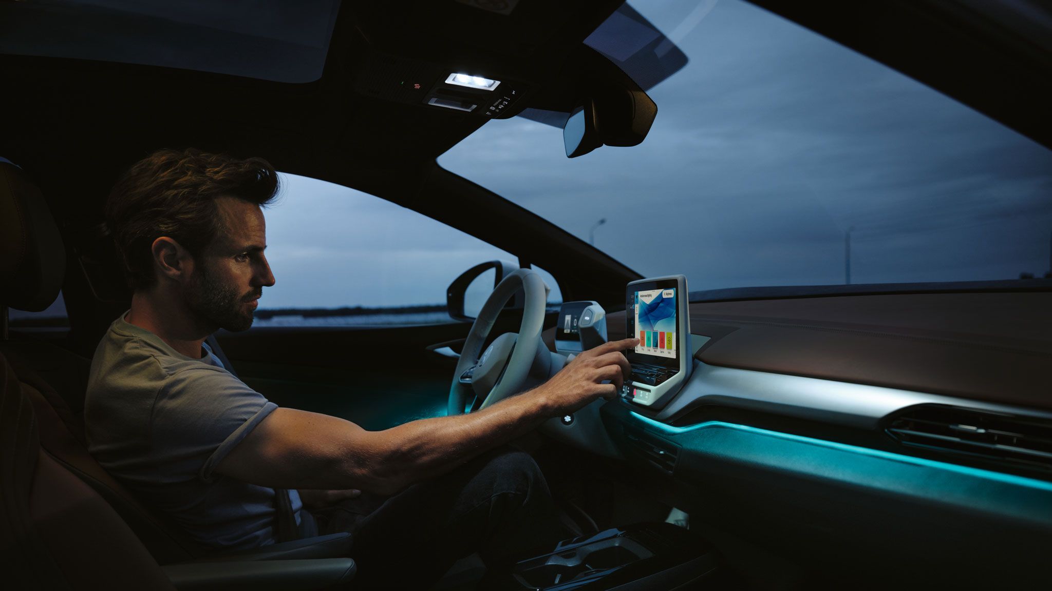 Ein Mann sitzt im VW ID.4 und bedient das Infotainmentsystem