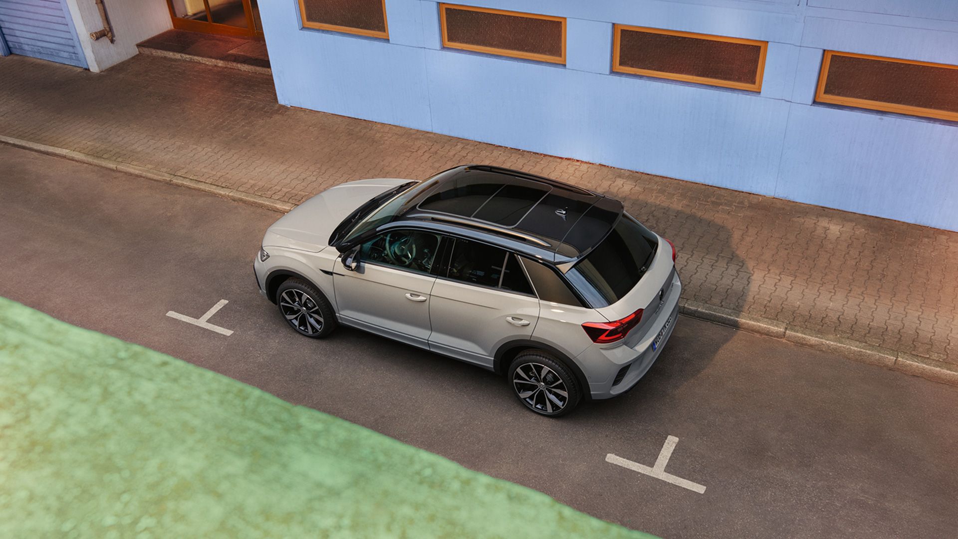 Blick von oben auf einen weißen VW T-Roc, parkend am Straßenrand. 