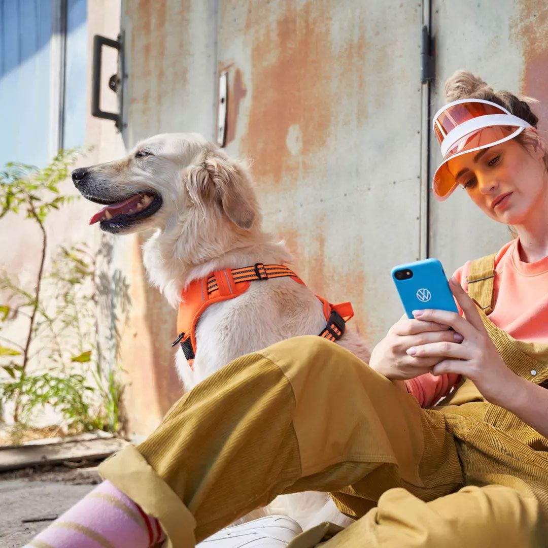 Eine Frau blickt auf ihr Smartphone, ein Hund ist bei ihr