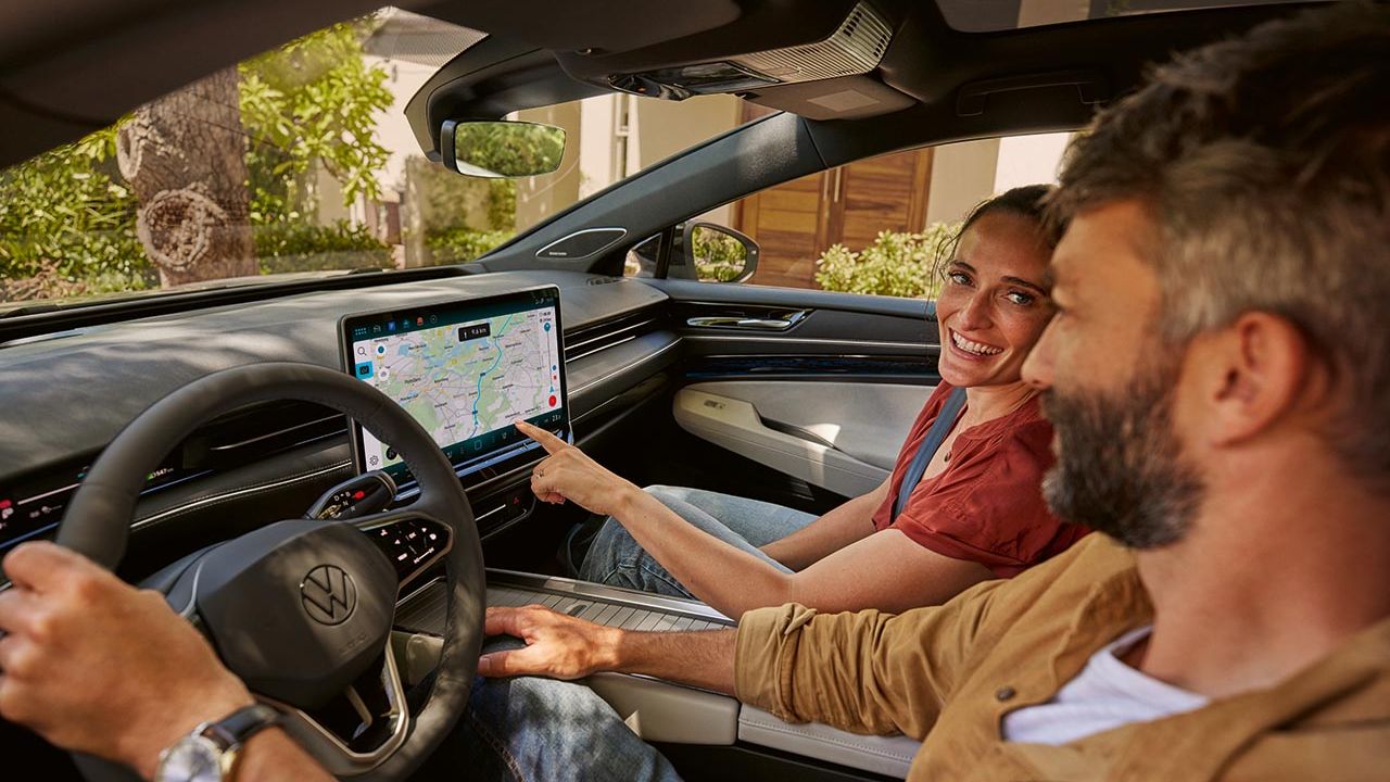 Mann und Frau sitzen im VW ID.7 und blicken auf das Display
