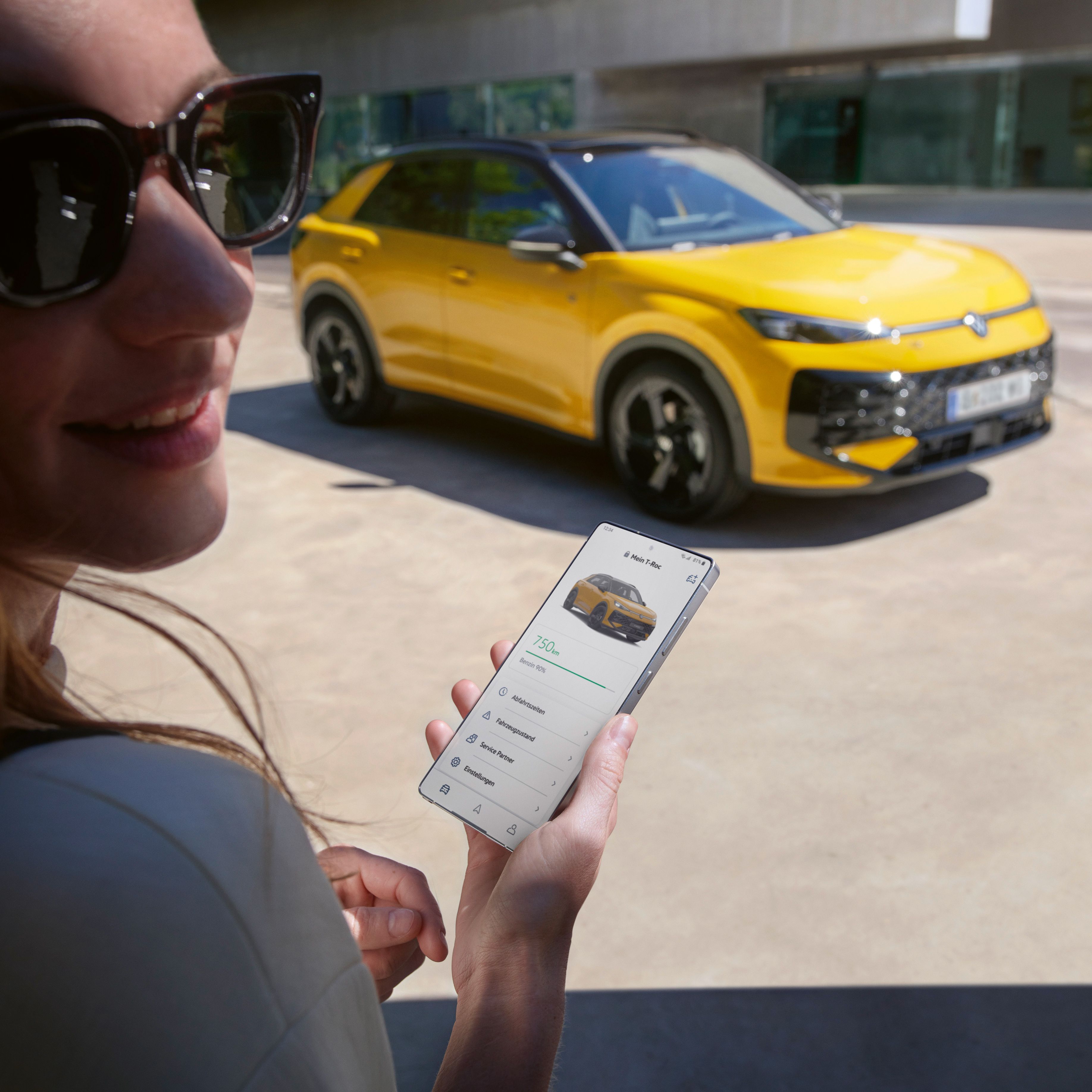 Eine Frau nutzt die App VW Connect nahe ihres VW T-Roc R-Line.