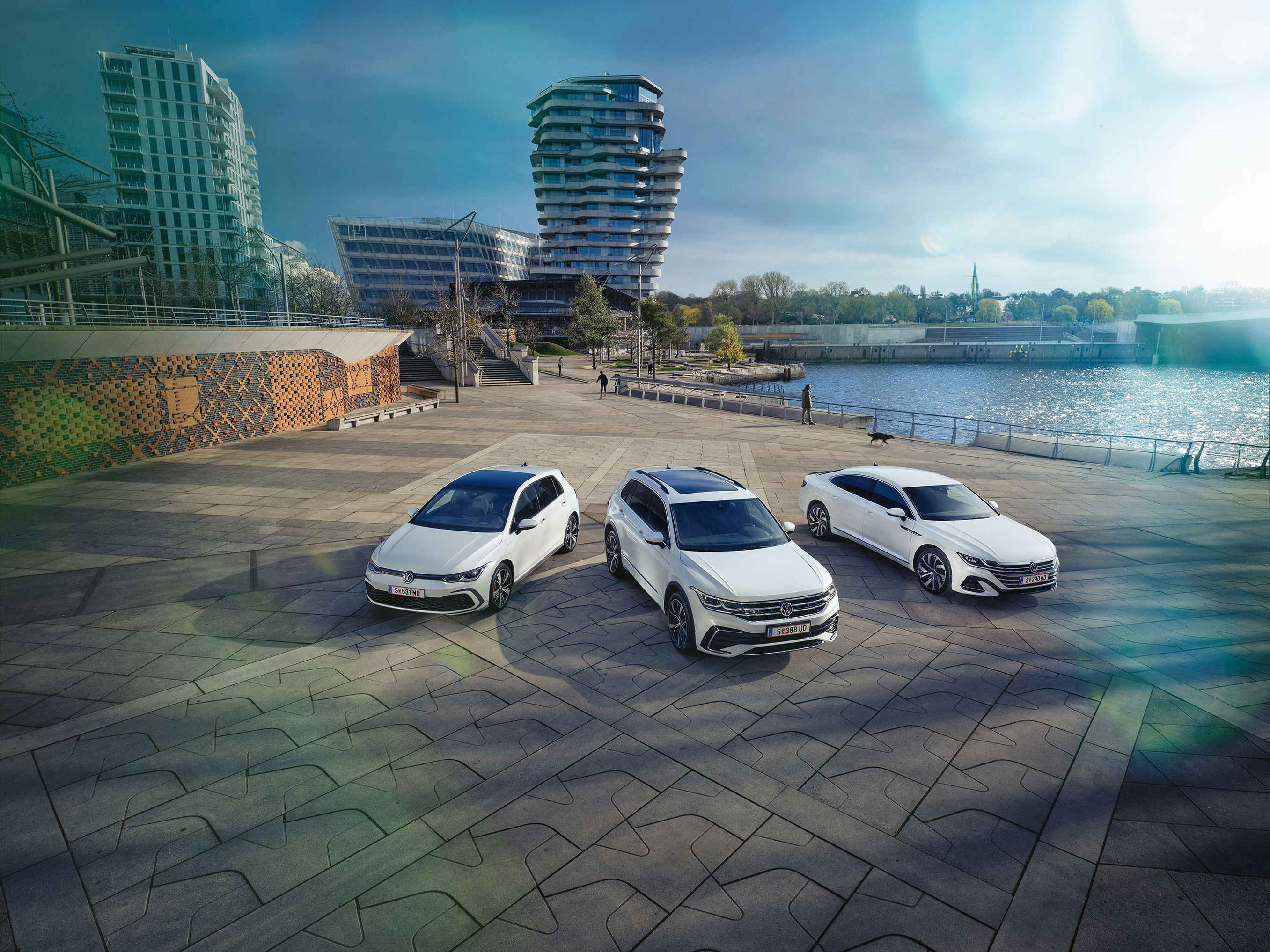 Drei weiße VW Lagerfahrzeuge parken am Hafen