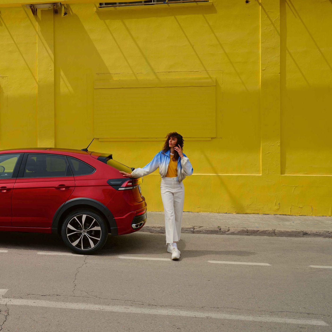 Ein roter VW Taigo steht vor einer gelben Wand auf einer Asphaltierten Strasse.