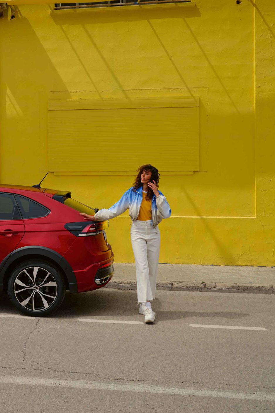 Ein roter VW Taigo steht vor einer gelben Wand auf einer Asphaltierten Strasse.