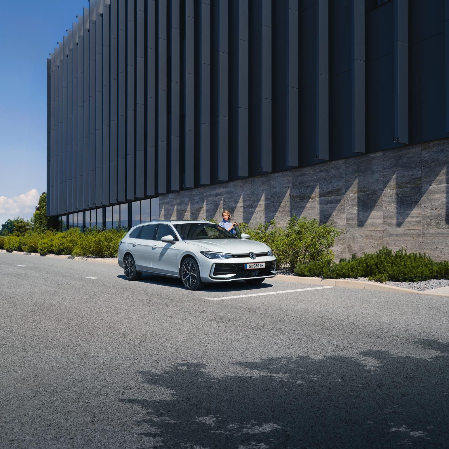 VW Passat in weiß parkt seitlich vor einem Gebäude.
