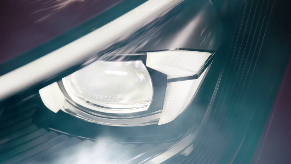 Nahaufnahme eines modernen Autoscheinwerfers. Der Scheinwerfer ist eingeschaltet und das Licht strahlt hell. Ein Teil des Fahrzeugkörpers ist ebenfalls zu erkennen.
