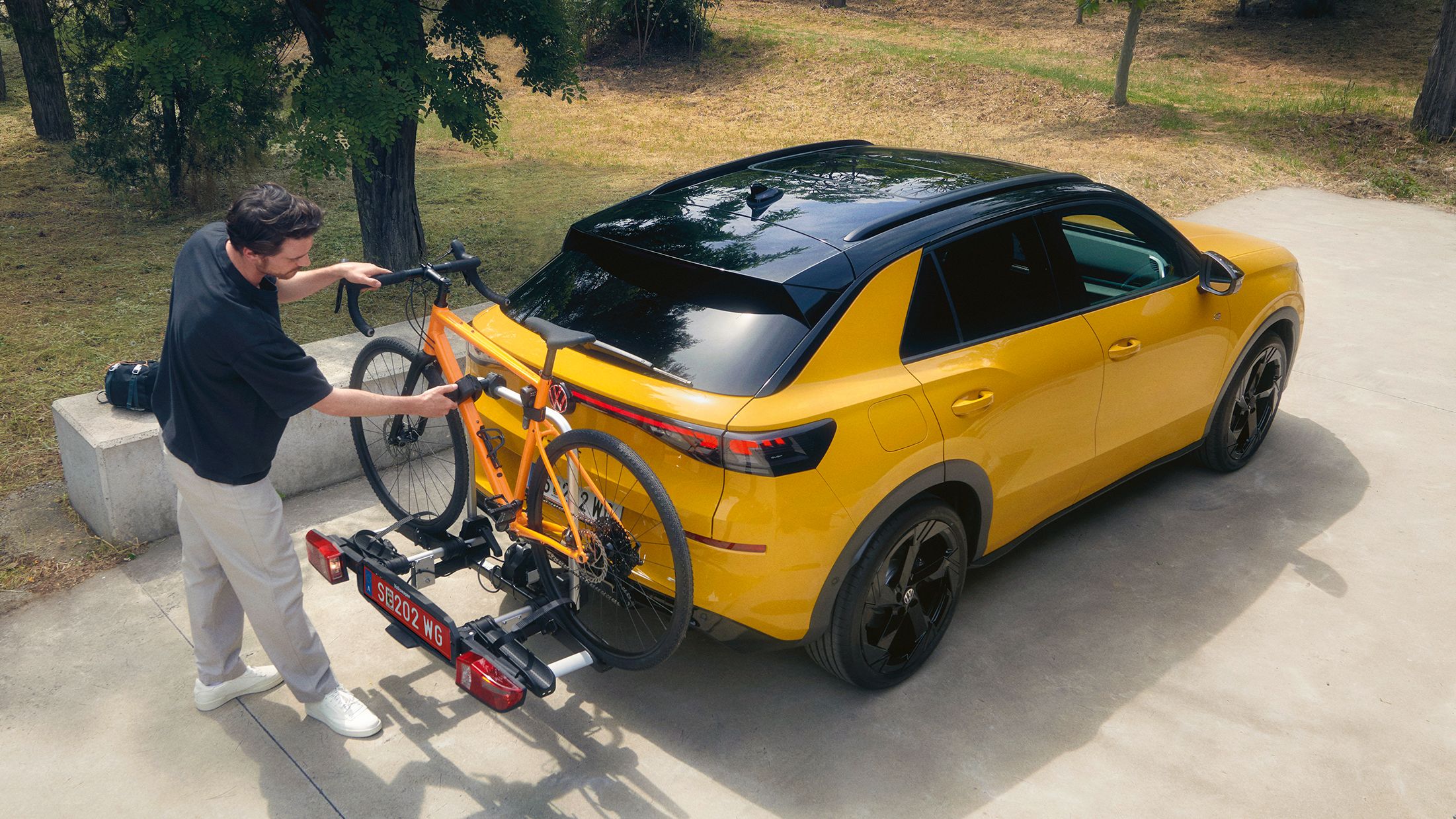 Ein Mann befestigt ein Fahrrad am Fahrradträger eines VW T-Roc R-Line.
